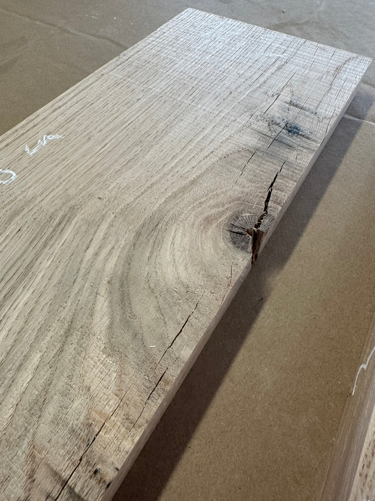 Détail du lot 004 : fissure près du bord, nœud et variations de teinte du chêne massif.